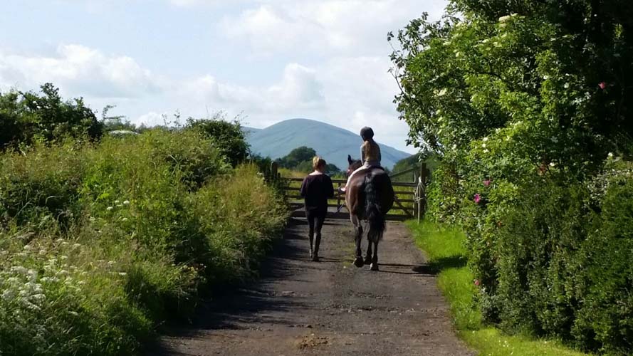 A rider and person walking beside them at Tullochan Stables